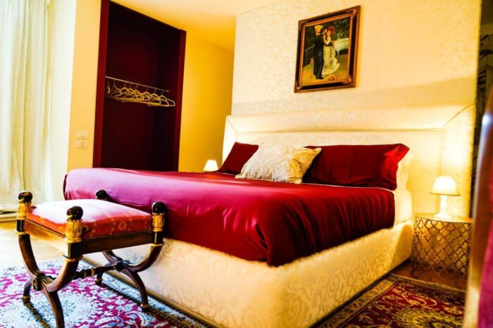 Letto matrimoniale con lenzuola rubino i una suite con arredi d'epoca